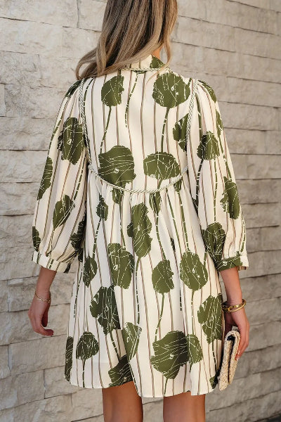 Woman wearing a green and white patterned dress against a stone wall.
