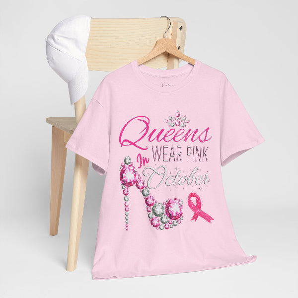 Pink t-shirt with 'Queens Wear Pink in October' text and breast cancer awareness ribbon on a wooden chair.