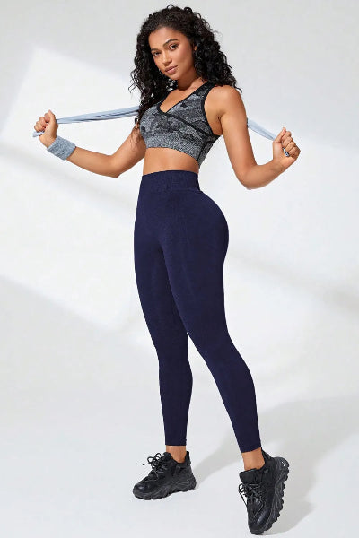 Woman holding resistance bands wearing a sports bra and leggings on a white background