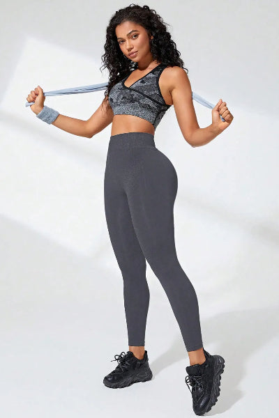 Woman in gray athletic outfit holding a resistance band against a white background