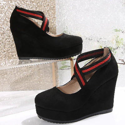 Black wedge sandals with red straps on a white surface