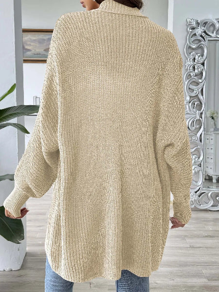 Person wearing a beige knitted cardigan in an indoor setting