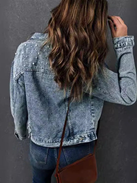 Person wearing a denim jacket with a plain background