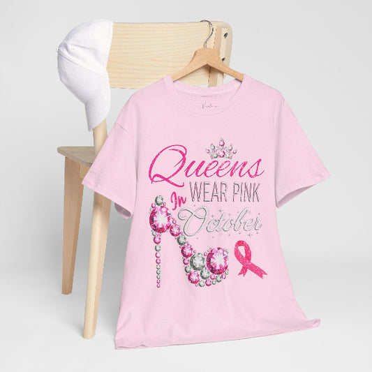 Pink t-shirt with 'Queens Wear Pink in October' text and breast cancer awareness ribbon on a wooden chair.