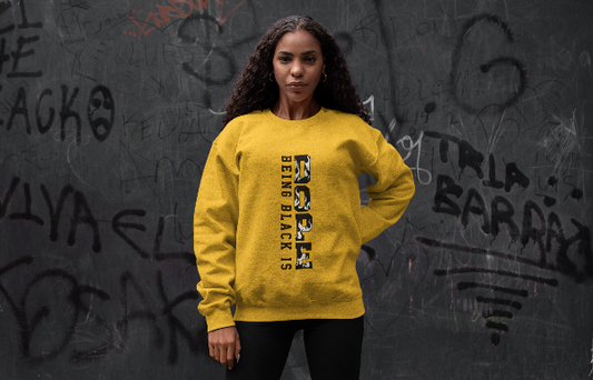 Person wearing a yellow sweatshirt with text in front of a graffiti-covered wall