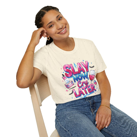 Person wearing a white t-shirt with colorful text and graphics, sitting on a chair.