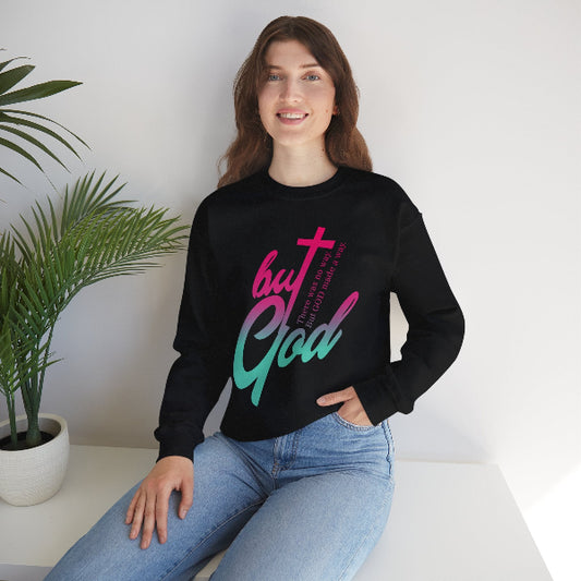 Person wearing a black sweatshirt with colorful text sitting on a white surface with a plant in the background