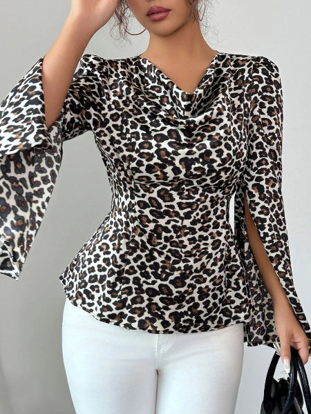 Woman wearing a leopard print top with white pants against a gray background