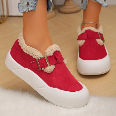Red shoes with white soles and fur trim on a light wooden floor.