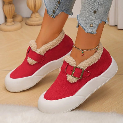 Red sneakers with white soles worn indoors on a wooden floor.