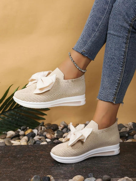 Beige sneakers with white soles worn by a person on a natural background