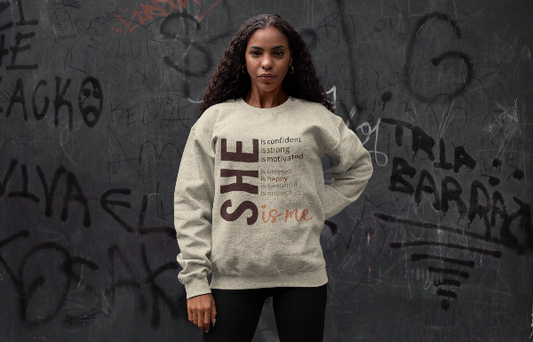 Woman wearing a sweatshirt with motivational text against a graffiti-covered wall
